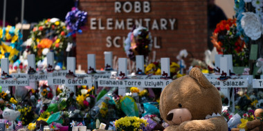 A large teddy bear is placed at a memorial in front of crosses bearing the names of the victims killed in this week's school shooting in Uvalde, Texas Saturday, May 28, 2022.