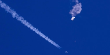 The remnants of a large balloon drift above the Atlantic Ocean, just off the coast of South Carolina, with a fighter jet and its contrail seen below it