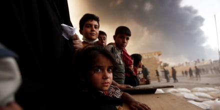Image: Newly displaced people wait to receive food supplies at a processing center for displaced people In Qayyara