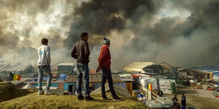 Image: Migrants stand on a hill overlooking the \"Jungle\" migrant camp in Calais