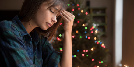 Image: A woman sits by a Christmas tree