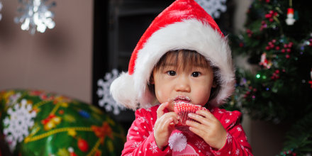 Close-Up Portrait Of Baby Girl Eating At Home During Christmas