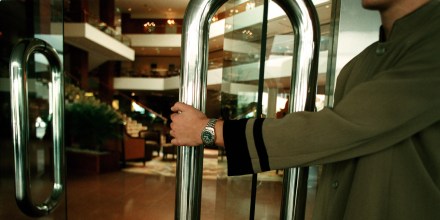 Image: A doorman opening the door to a luxury hotel foyer, 25 June 2002