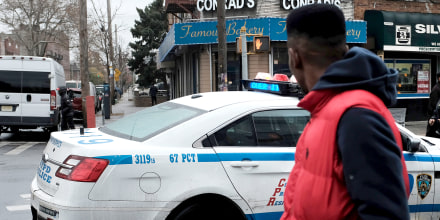 People walk past a police car in the in the Brownsville neighborhood of Brooklyn on Nov. 18, 2019 in New York.