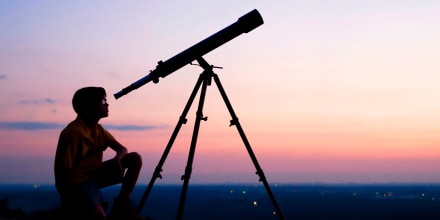 Person stargazing at night with a telescope. Shop the best telescopes and binoculars to watch meteor showers.