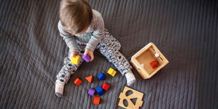 Little boy on a bead spread playing with shape blocks