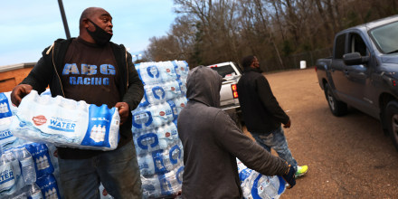 Image: Benjamin Williams and Ben Mitchell help to distribute bottled water in the parking lot of Forest Hill High School on March 5, 2021 in Jackson, Miss