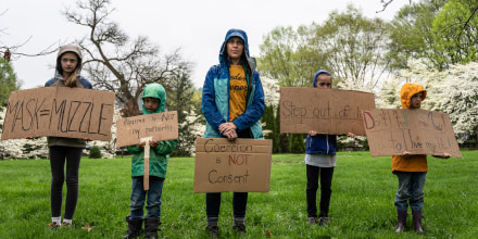 Image: A mother and her children hold anti-vaccination and anti-Covid19 mandate signs in protest on state capitol grounds on April 14, 2021 in Frankfort