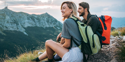 Couple relaxing after hiking and taking a break, wearing backpacks