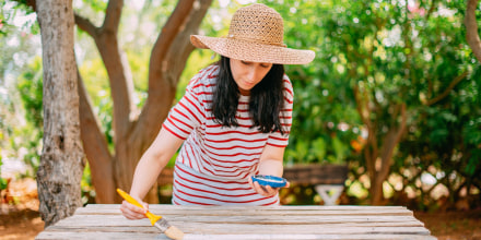 Woman Painting Wooden Table. DIY in the Garden