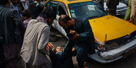 Image: Men try to help a wounded woman and her wounded child after Taliban fighters use guns fire, whips, sticks and sharp objects to maintain crowd control over thousands of Afghans who continue to wait outside the Kabul Airport