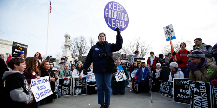 Anti-abortion activists kneel down and pray as they surround abortion rights activist Luanne Smith of Burke, Va., during the annual \"March for Life\" in Washington on Jan. 22, 2010.