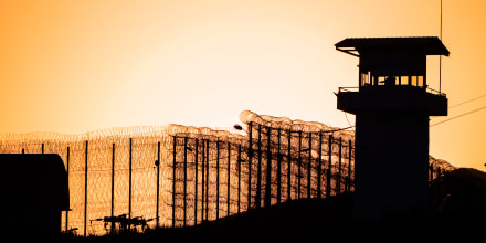 Silhouette of barbed wires and watchtower of prison.