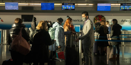 Image: A staff member assists passengers at John F. Kennedy International Airport during the spread of the Omicron coronavirus variant in Queens, New York City, on Dec. 26, 2021.