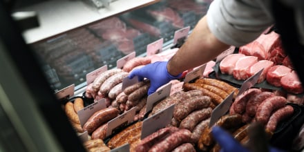 A worker places pork sausages into a display case at Baron's Quality Meats in Castro Valley Marketplace in Castro Valley, Calif., on Jan. 12, 2022.