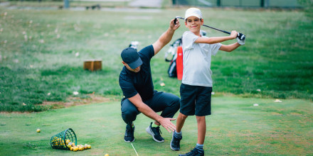 Golf Instructor Teaching Young Boy How to Swing