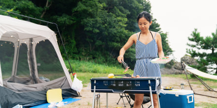 Woman grilling vegetables on a bbq whilst camping