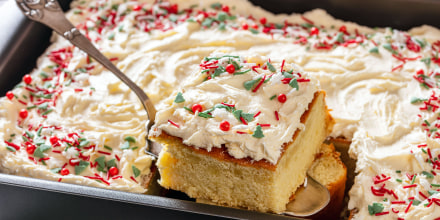 christmas vanilla sheet cake with whipped buttercream frosting garnished with sprinkles on cake shovel in baking dish