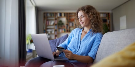 Smiling woman doing online shopping on laptop at home