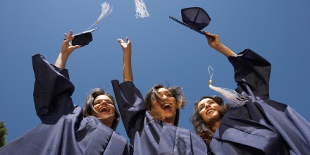Three female graduate students throwing mortar boards, low angle view