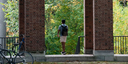 A student walks between dormitory buildings on the campus of Dartmouth College in Hanover, N.H., on Oct. 15, 2021.