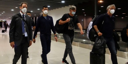 El tenista serbio Novak Djokovic camina por el aeropuerto de Melbourne, custodiado por personal de seguridad y miembros de su equipo, antes de abandonar Australia el 16 de enero de 2022.