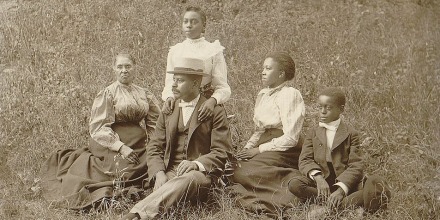 An African American family sits for a portrait in the late 19th century.