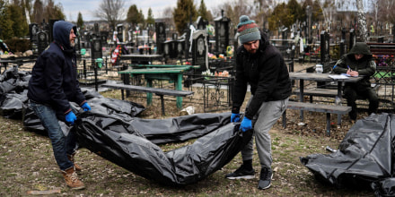 Workers line up bodies for identification by forensic personnel at a cemetery in Bucha, Ukraine, on April 6, 2022.