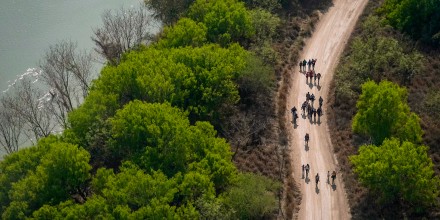 Migrants walk on a dirt road along the Rio Grande in Mission, Texas, on March 23, 2021, after crossing the U.S.-Mexico border.
