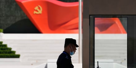 A security guard stands near a sculpture of the Chinese Communist Party flag