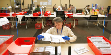 Una trabajadora electoral inspecciona una boleta enviada por correo en California.