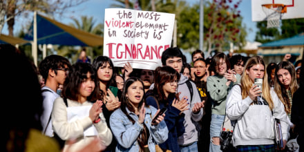Un grupo de aproximadamente 30 estudiantes de un bachillerato en California aplaude a un orador durante una protesta a favor de que haya enseñanzas de teoría crítica de la raza. Una persona sostiene un cartel que dice "El elemento más violento de una sociedad es la ignorancia".