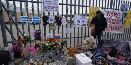 Un altar con velas y fotos cubre la cerca afuera del centro de detención de migrantes en Ciudad Juárez, México, el jueves 30 de marzo de 2023. 