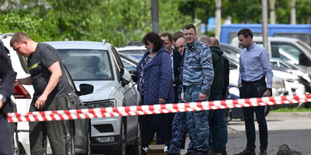 Law enforcement officers and investigators are seen outside a damaged multi-storey apartment building after a reported drone attack in Moscow on May 30, 2023.