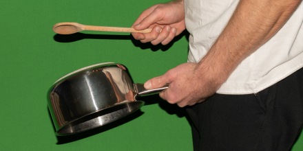 Hitting a pan with a wooden spoon.