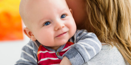 Mother holding baby son over shoulder