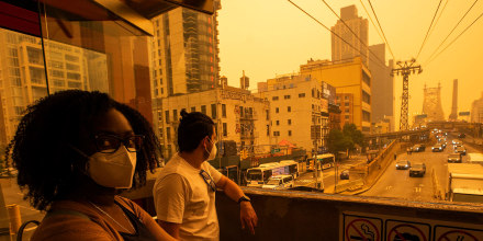 People wear masks as they wait for the tramway to Roosevelt Island as smoke from Canadian wildfires casts a haze over New York City on June 7, 2023.