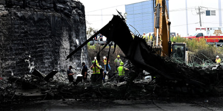 Workers inspect and clear debris from a section of the bridge that collapsed on Interstate 95 after an oil tanker explosion in Philadelphia