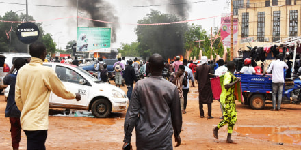 People crowd the street while supporters of the Nigerien defense and security forces attack the headquarters of the Nigerien Party for Democracy and Socialism