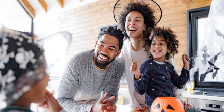 Happy African American family talking while having Halloween celebration at home.