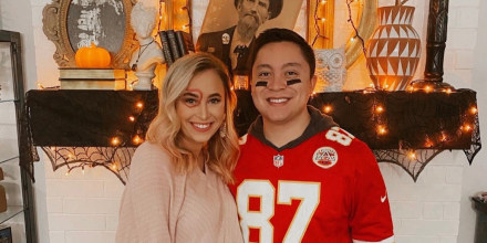 A woman with a heart around her eye and a white shirt on smiles on the left and a man in a 87 Kansas City jersey smiles on the right.
