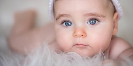 Portrait of cute baby girl lying on bed