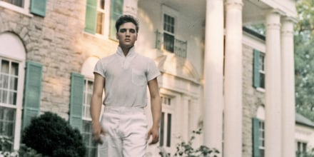 Elvis Presley dressed in all white strolls the grounds of his Graceland estate.