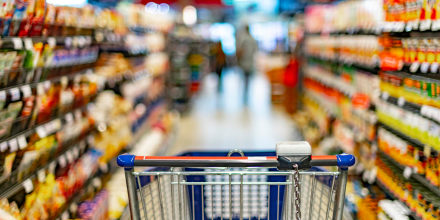 A shopping cart by a store shelf in a supermarket