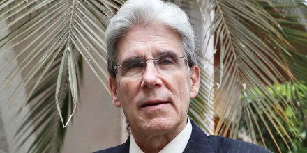 Julio Frenk poses for a portrait in front of a palm tree