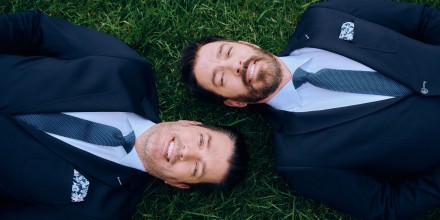 Portrait of Property Brothers Jonathan and Drew Scott laying in grass at the garden on the 12th floor of 30 Rock.