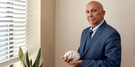 Fernando Taveras stands for a portrait holding a prop of a human brain