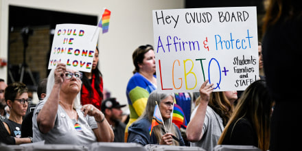 People hold signs in an auditorium