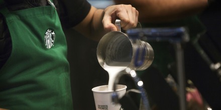 A barista pours frothed milk into a drink inside a Starbucks Corp