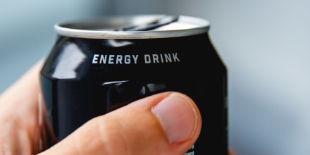 a close up of a hand holding a can of energy drink